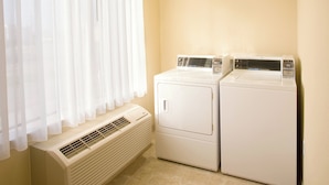 A laundry room with two stacked washers and dryers, a vent, and a window with sheer curtains. - Holiday Inn Express Hotel & Suites Victoria by IHG (Victoria)