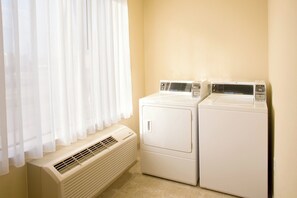A laundry room with two stacked washers and dryers, a vent, and a window with sheer curtains. - Holiday Inn Express Hotel & Suites Victoria by IHG (Victoria)
