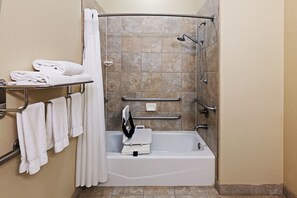 A bathroom with a bathtub, grab bars, a towel rack, and a shower curtain.