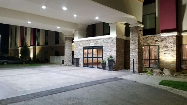 Entrada de hotel con fachada de piedra, grandes ventanales y zona de estacionamiento techada.