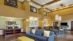 A hotel lobby with a reception desk, seating area, and dining space.