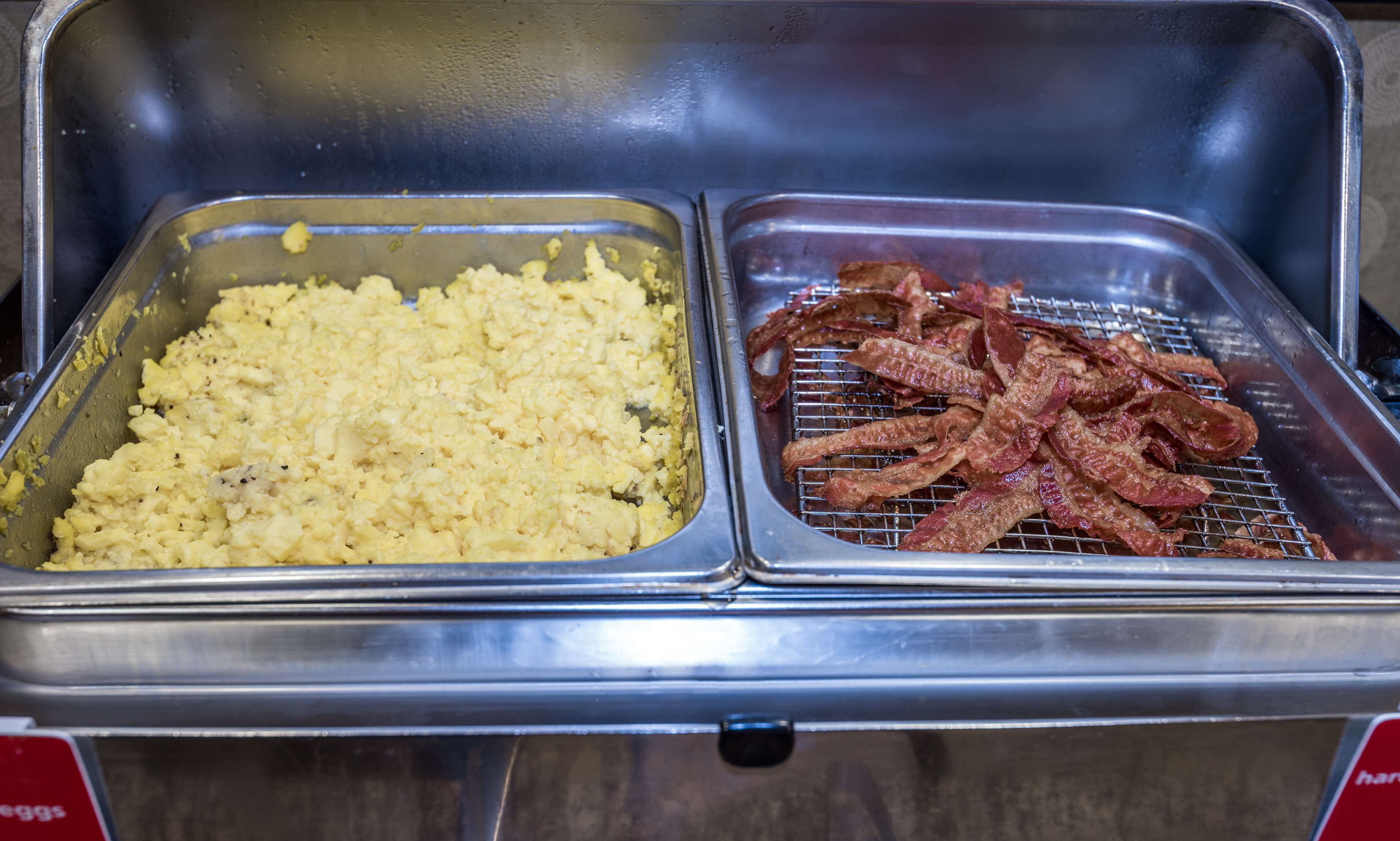 A buffet with scrambled eggs and bacon.