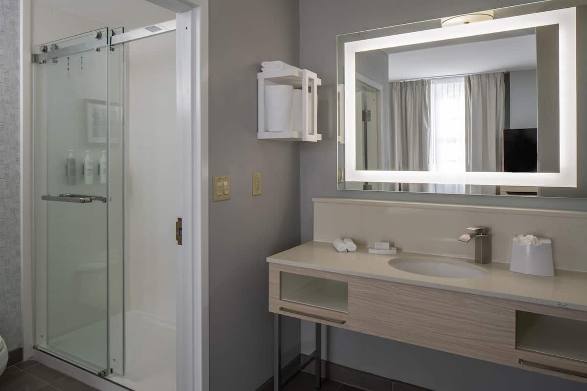 A bathroom with a glass shower enclosure, a sink with a mirror, and a towel rack.
