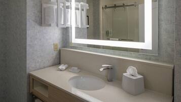 Un baño moderno con un espejo grande, un lavabo, un dispensador de toallas y un porta papel higiénico.