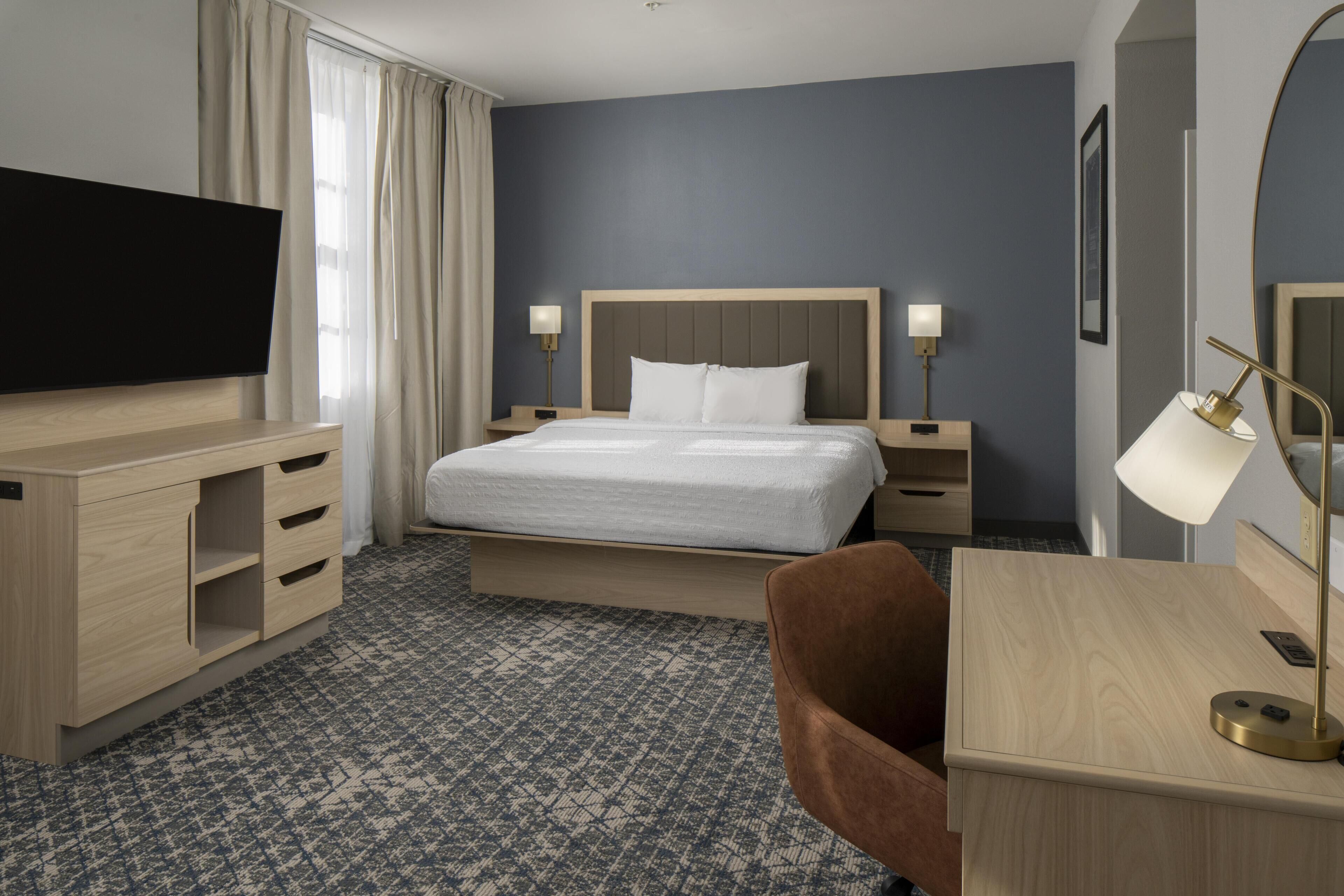 Une chambre d’hôtel avec un lit, un bureau, une télévision et une lampe.