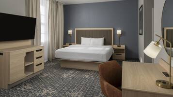 Een hotelkamer met een bed, een bureau, een televisie en een lamp.