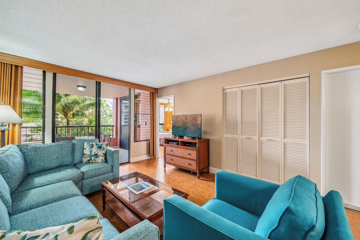 A living room with a sofa, armchair, coffee table, and a television on a wooden cabinet.