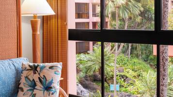 A room with a view of a tropical garden, a blue pillow, and a lamp.