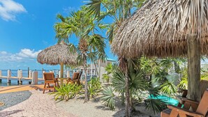 A beachside resort with thatched umbrellas, wooden lounge chairs, and palm trees. - Anchorage Resort & Yacht Club (Key Largo)