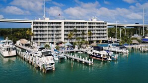 A marina with docked boats, a multi-story building with balconies, and a bridge in the background. - Anchorage Resort & Yacht Club (Key Largo)