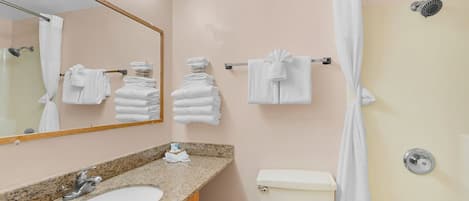 A bathroom with a sink, mirror, towel rack, toilet, and shower curtain.