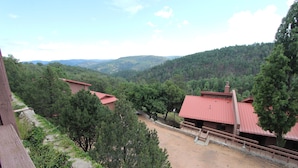 A building with a red roof, surrounded by trees and a hilly landscape. - Crown Point Resort (Ruidoso)
