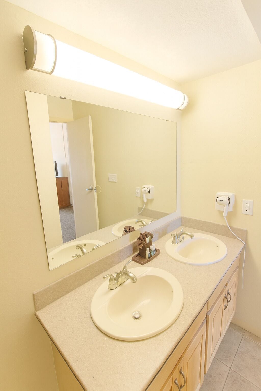 A bathroom with two sinks, a large mirror, and a light fixture above the mirror.