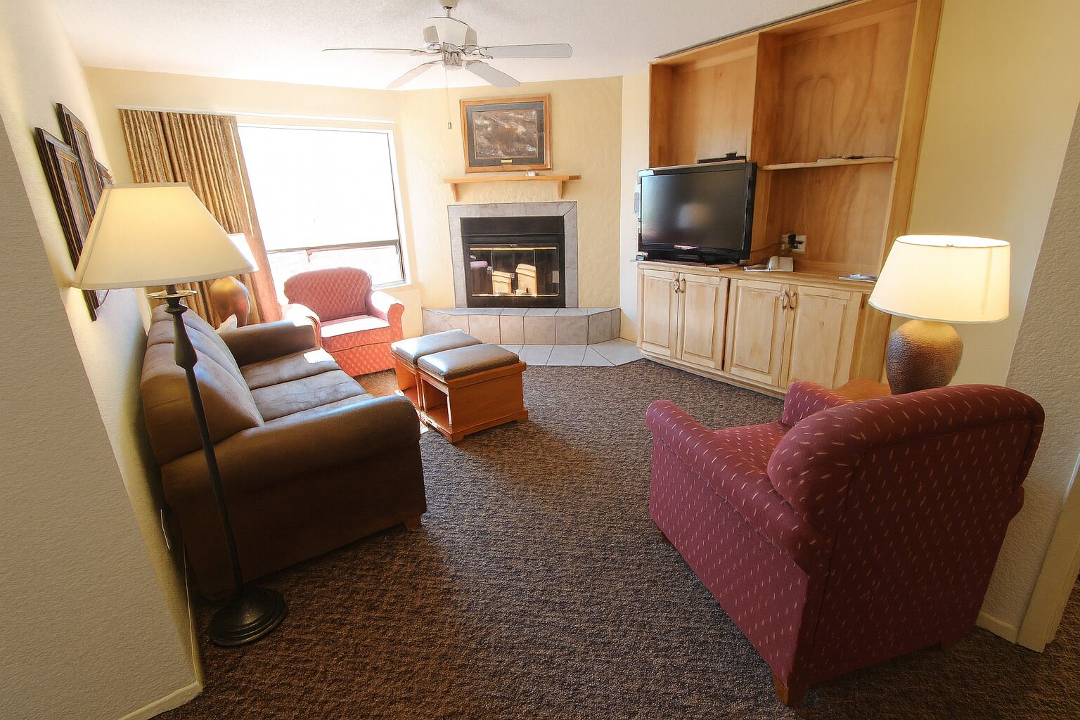 A living room with a fireplace, a television, and two armchairs.