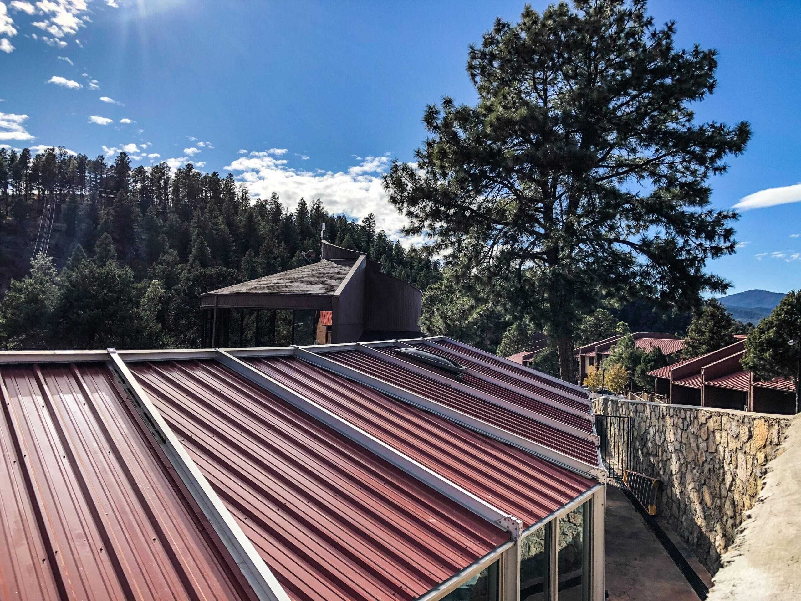 A red metal roof with a stone wall and a pathway leading to a building.
