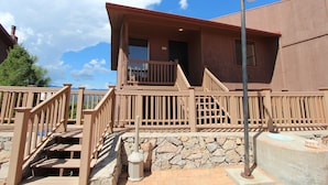 A two-story building with a wooden balcony, stone steps, and a stone wall. - Crown Point Resort (Ruidoso)