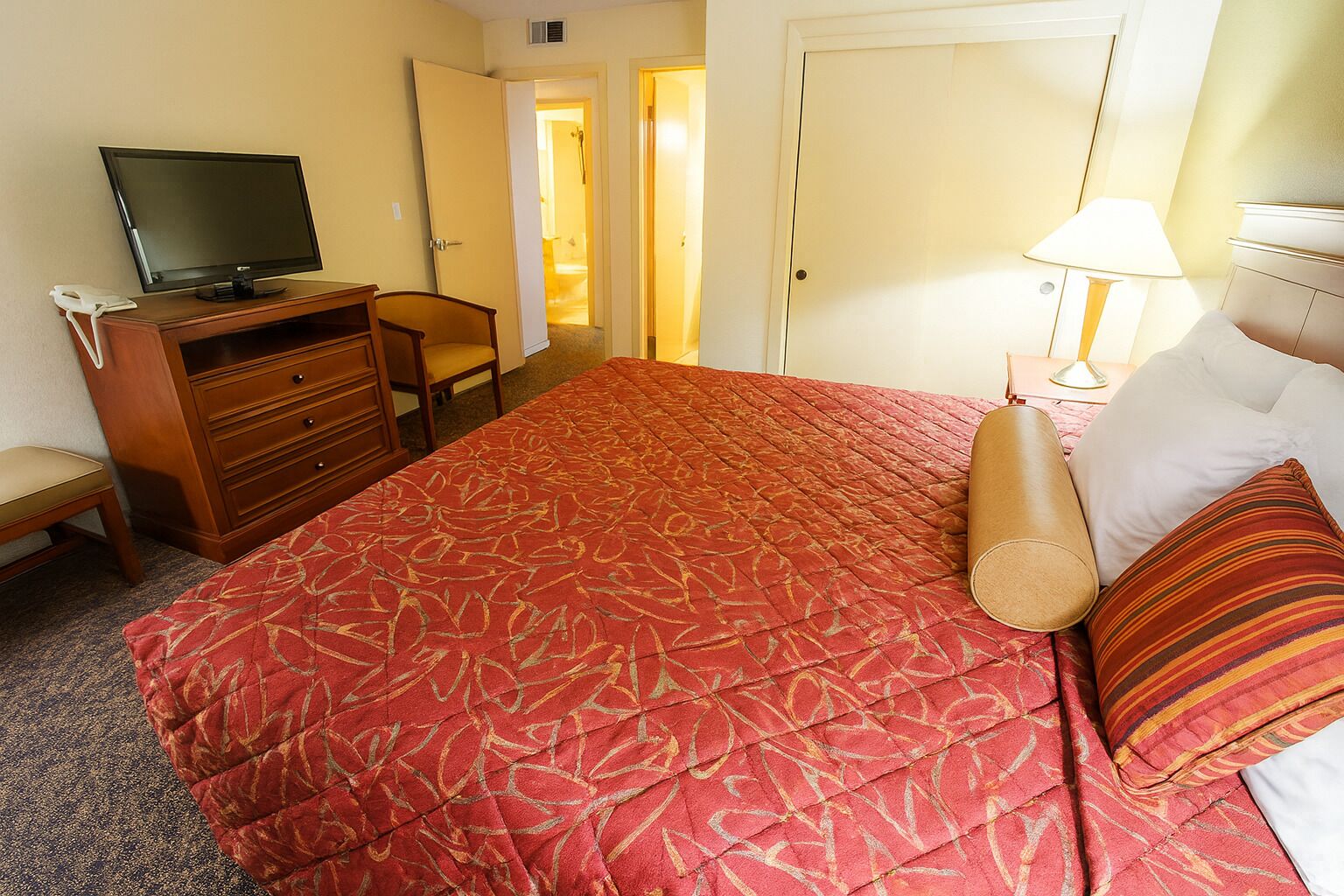 Een hotelkamer met een bed, een bureau met een computer, een stoel, een televisie en een lamp.