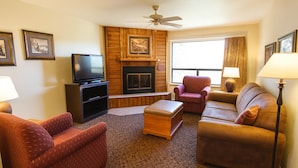 A living room with a fireplace, a television, and two sofas. - Crown Point Resort (Ruidoso)