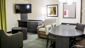 A hotel room with a flat-screen TV, a desk, a conference table, and a chair. - Candlewood Suites Richmond North Glen Allen by IHG (Glen Allen)