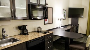 A compact hotel kitchen with a microwave, coffee maker, and a small dining area with a table and chairs. - Candlewood Suites Richmond North Glen Allen by IHG (Glen Allen)