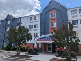 A multi-story hotel with a modern design, featuring a prominent entrance with a sign reading "Candlewood Suites."