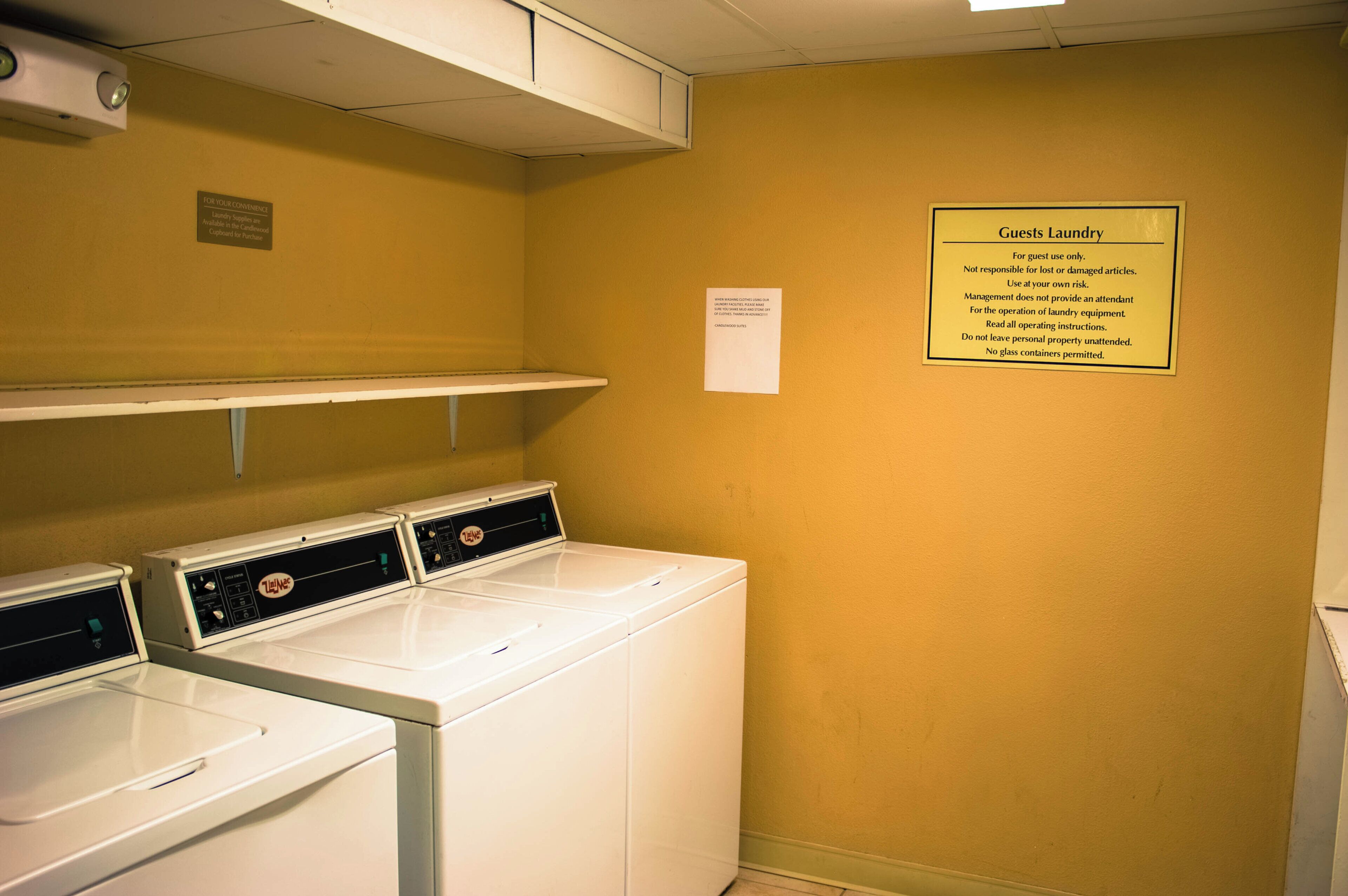 Un espace dédié à la buanderie, avec un panneau indiquant qu’il est réservé à l’usage des clients, ainsi qu’une note expliquant le fonctionnement des appareils de lavage.