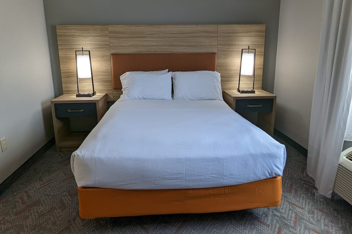 Hotellihuone, jossa on suuri sänky, kaksi yöpöytää ja kaksi lamppua.