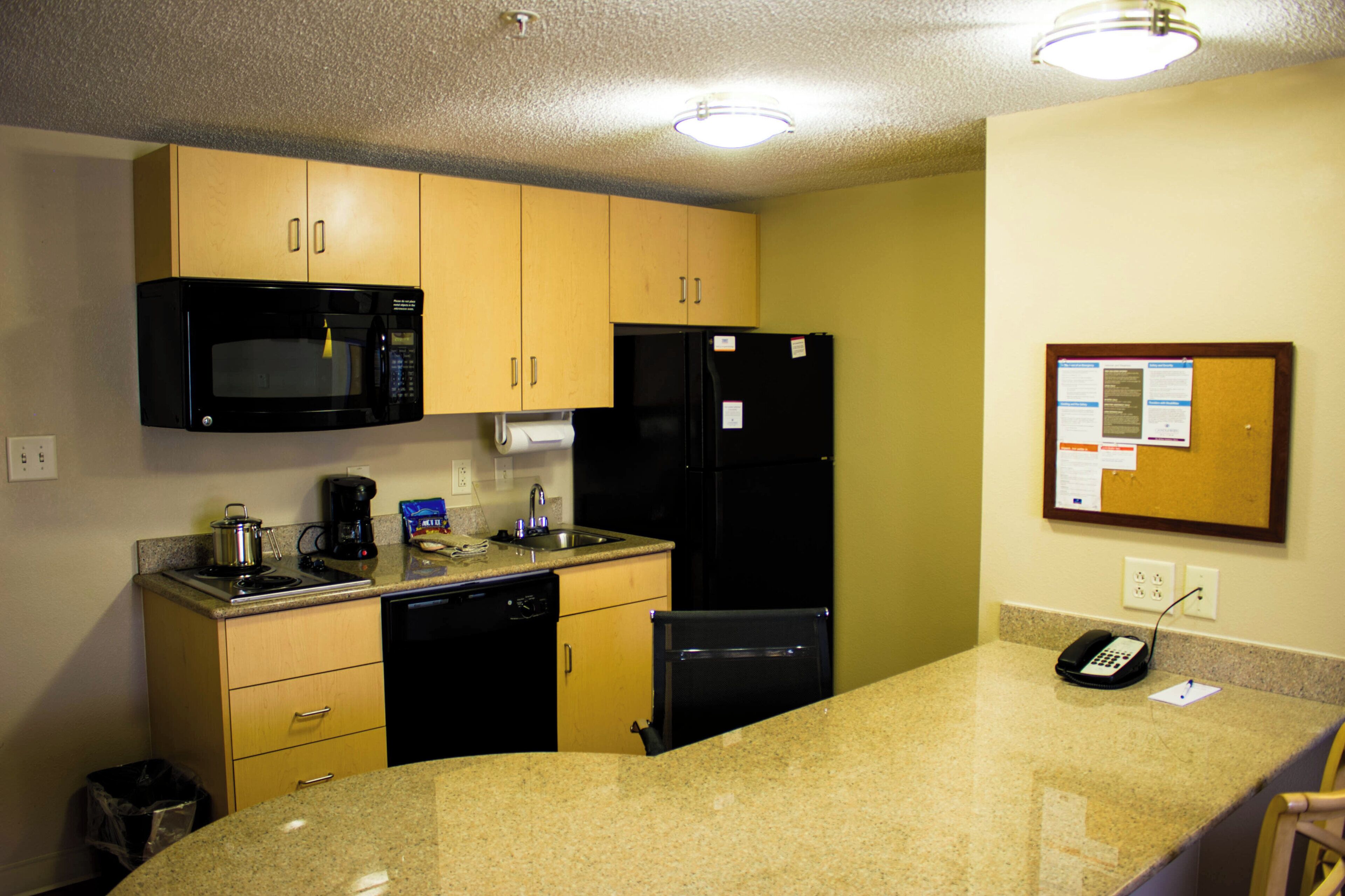 A compact kitchen with a microwave, refrigerator, coffee maker, and a small trash bin.