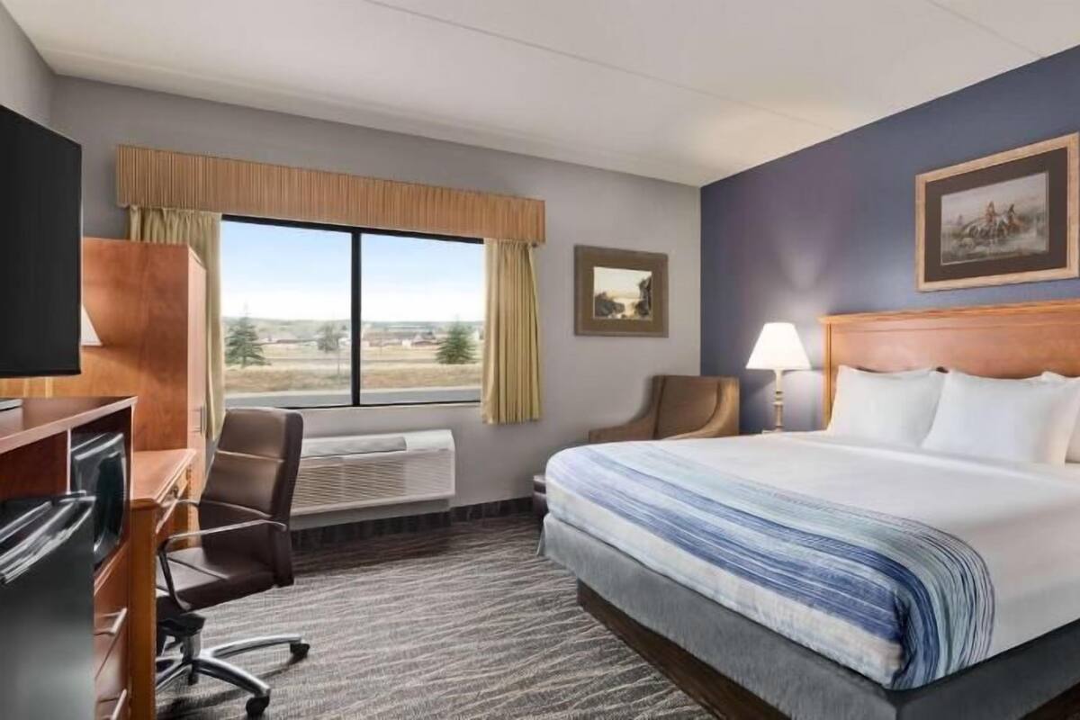 Ein Hotelzimmer mit Bett, Schreibtisch, Stuhl und einem großen Fenster mit Blick.