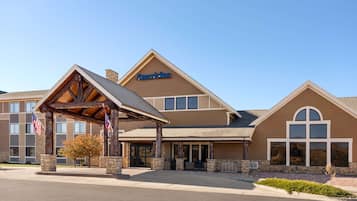 Um hotel com uma bandeira americana em destaque, entrada coberta e uma placa com a inscrição "AmericInn".