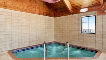 A spa area with a hot tub, wooden ceiling, tiled walls, and a window.
