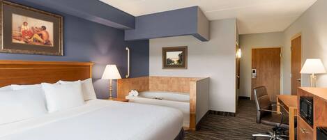 Une chambre d’hôtel avec un grand lit, un bureau, une chaise, un four à micro-ondes et une salle de bain avec une baignoire.