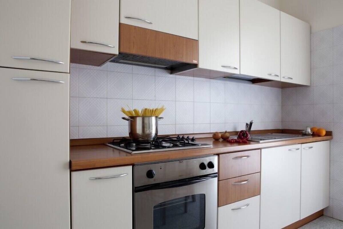 A modern kitchen with white cabinets, a stainless steel oven, and a gas stove.