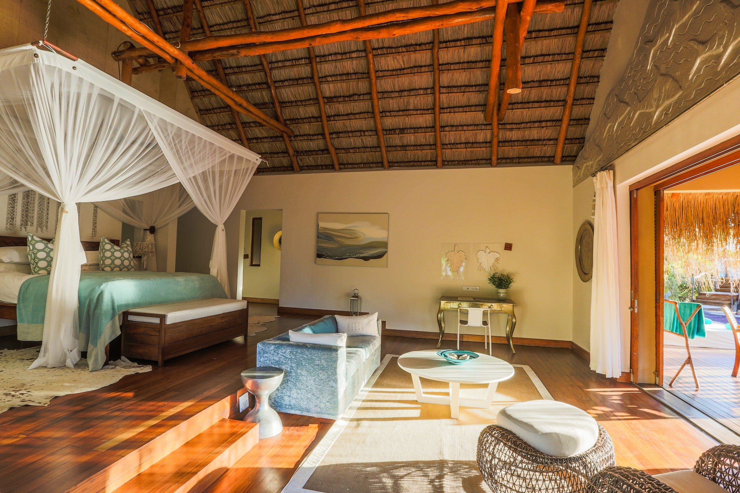 A bedroom with a canopy bed, a sofa, a coffee table, and a view of the outdoors.