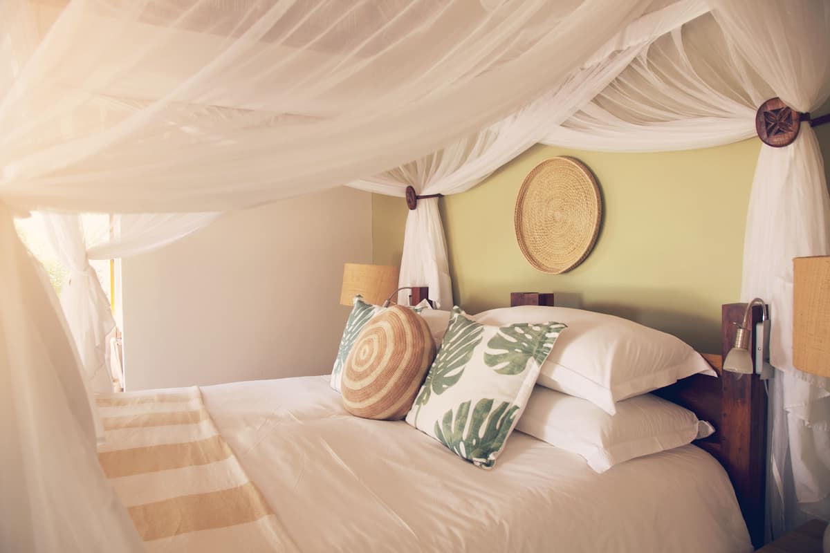 Un lit à baldaquin, avec une literie à rayures et des coussins décoratifs.