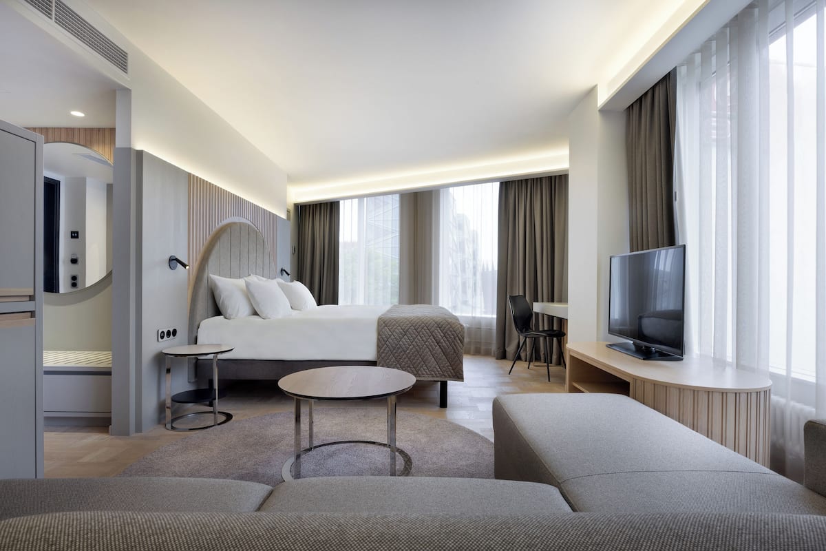 Une chambre d’hôtel moderne dotée d’un grand lit, d’une télévision, d’un coin salon et d’une petite table.