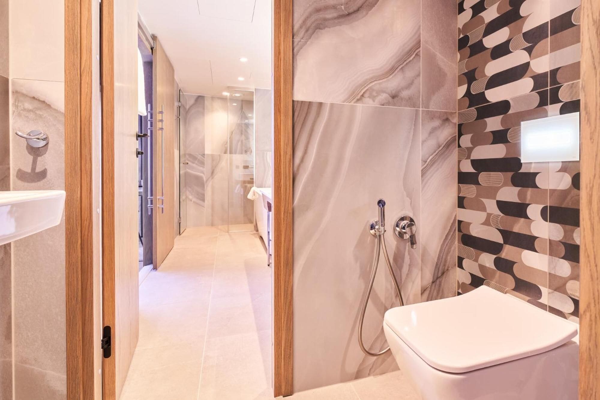 Ein modernes Badezimmer mit Marmorwand, einer Dusche und einer Toilette.