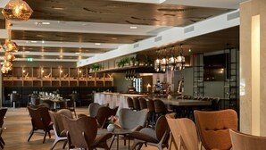 Un interior de restaurante moderno con suelo de madera, sillas contemporáneas e iluminación colgante.