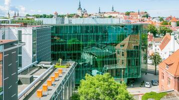 A modern building with a glass facade, surrounded by traditional architecture and a clear sky.