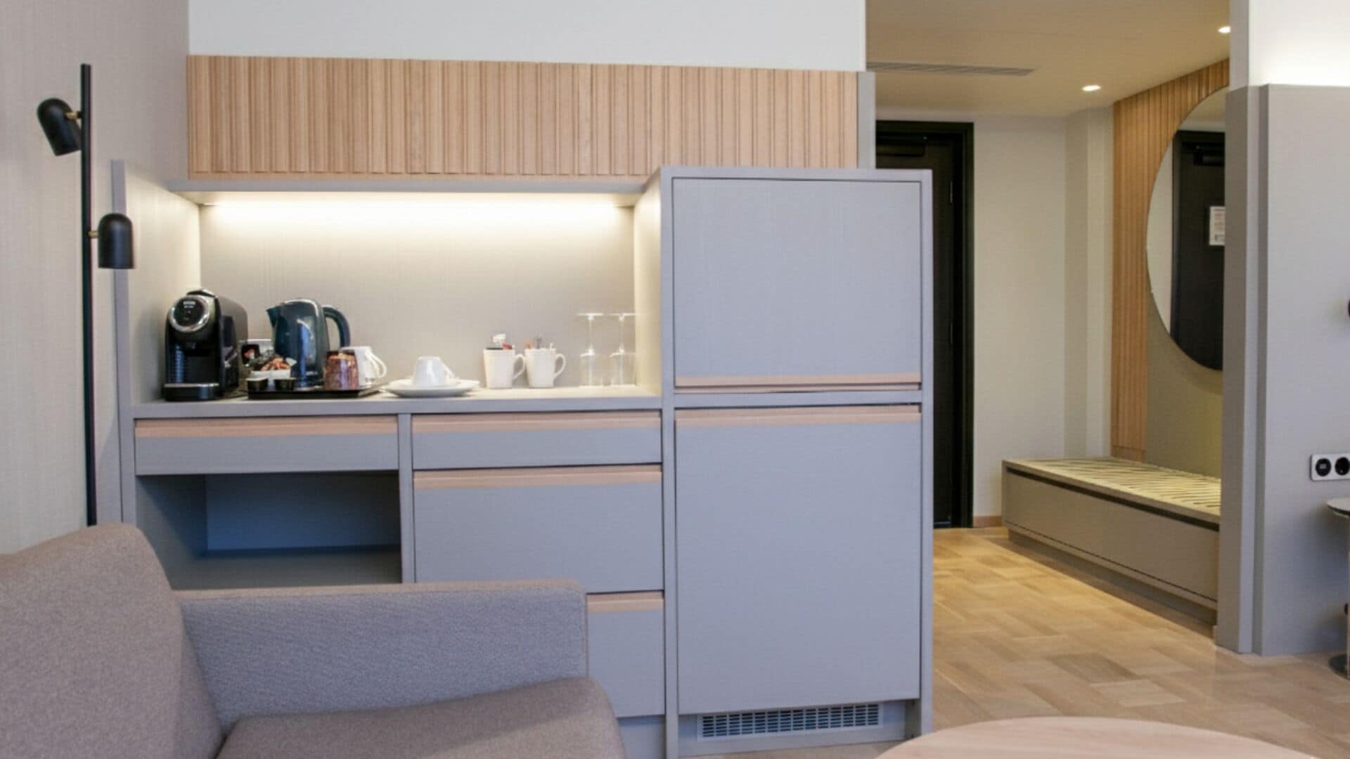Ein kompaktes Hotelzimmer mit Küchenzeile, einem Bett und einer Sitzecke.