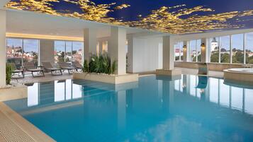 Una amplia piscina cubierta con vistas despejadas del paisaje urbano a través de grandes ventanales.