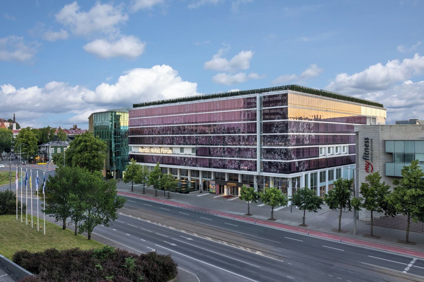A modern hotel with multiple floors, a prominent Nordic Hotel Forum sign, and a fitness center.