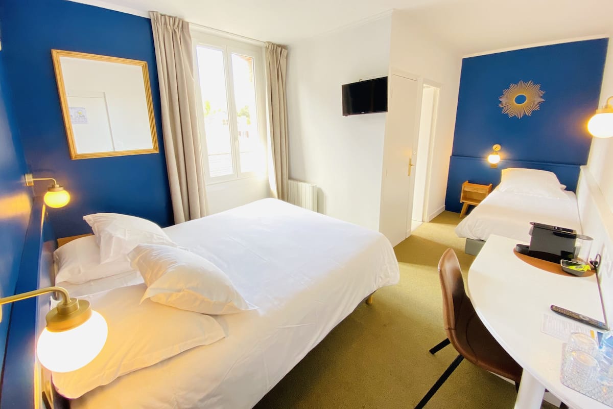 Habitación de hotel con dos camas, un escritorio, una silla, un televisor y una ventana con cortinas.