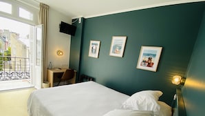 Una habitación de hotel con cama, escritorio, silla y balcón.