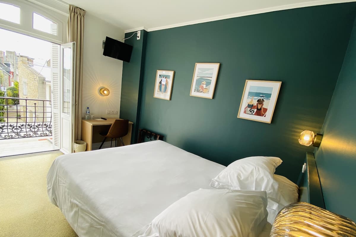 Una habitación de hotel con cama, escritorio, silla y balcón.