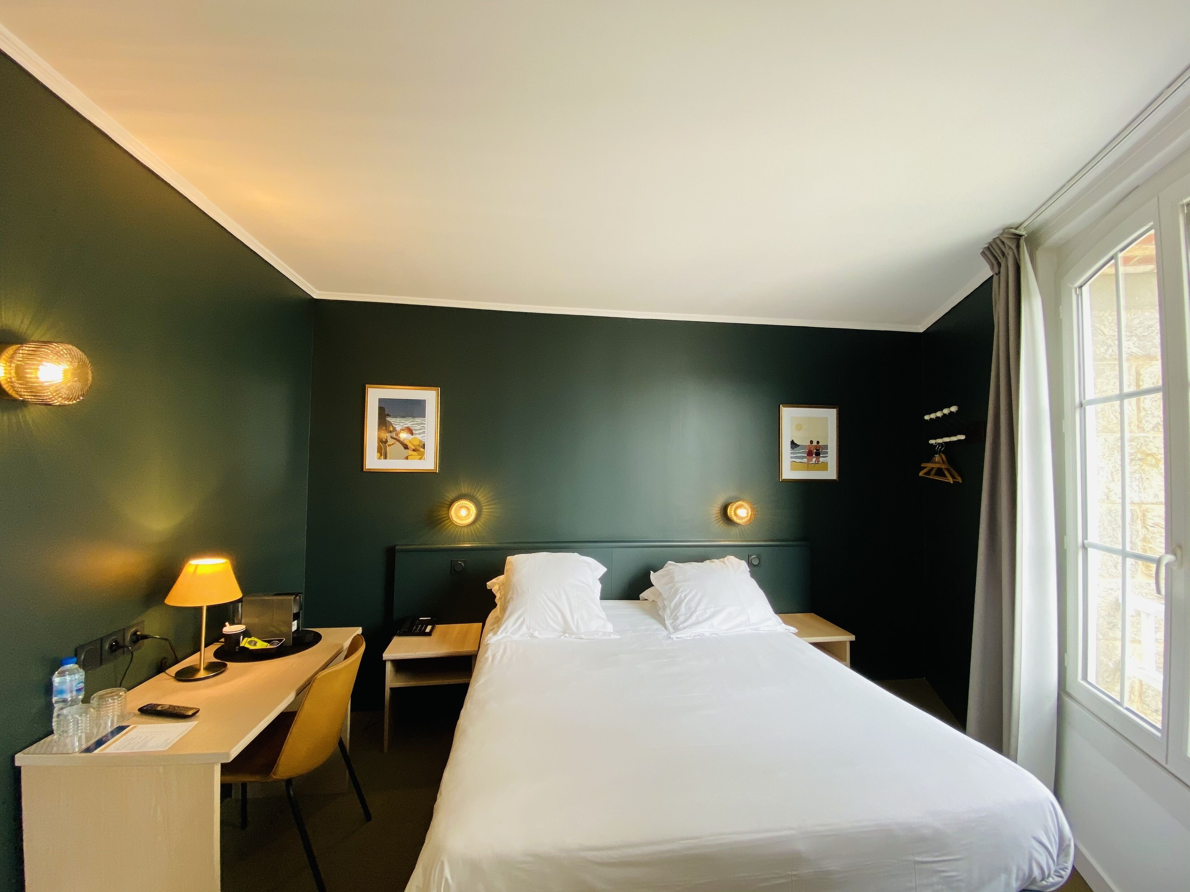 Una habitación de hotel con cama, escritorio, silla y dos lámparas de noche.