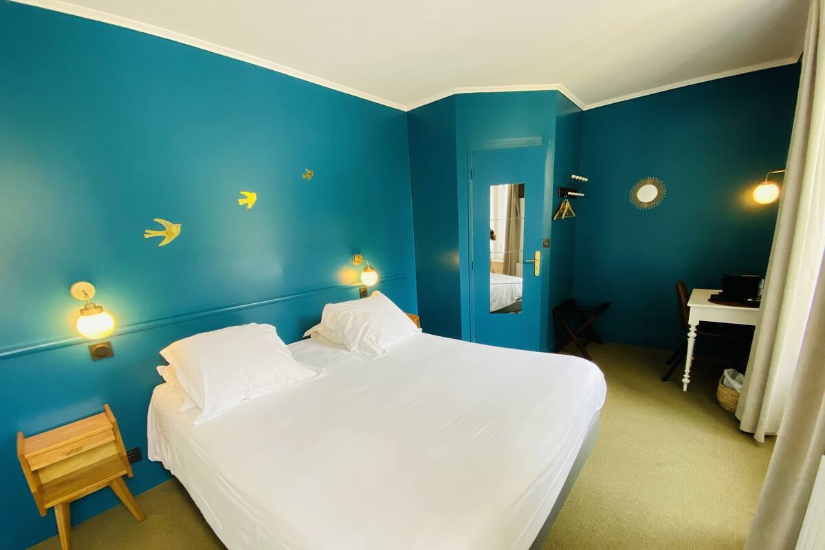 Una habitación de hotel con una cama grande, un escritorio y un espejo.