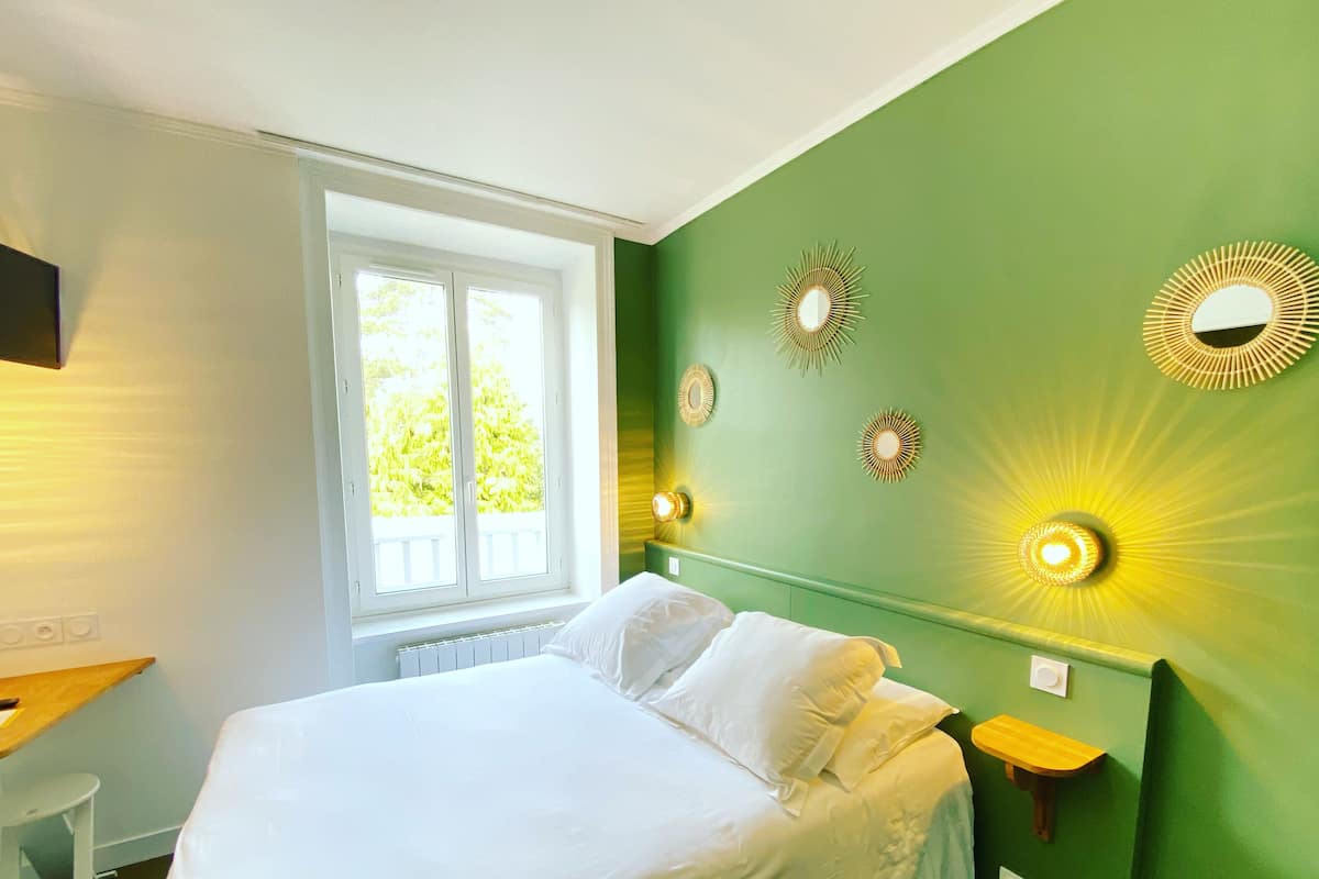 Un dormitorio con cama, ventana e iluminación en la pared.