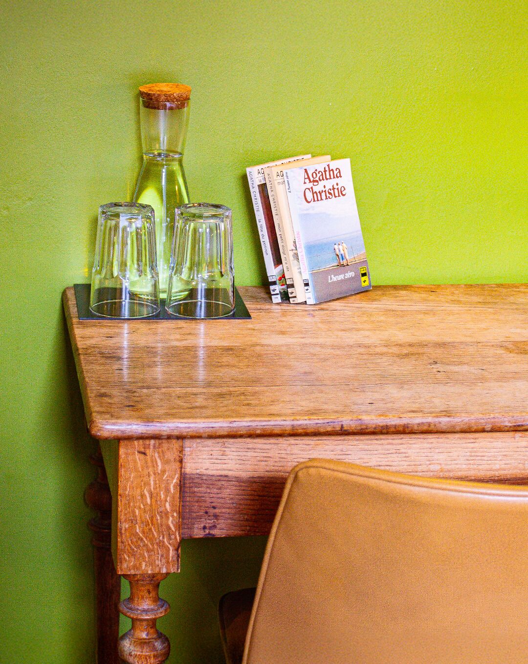 Une table en bois sur laquelle se trouvent un livre intitulé « Agatha Christie » et deux verres.