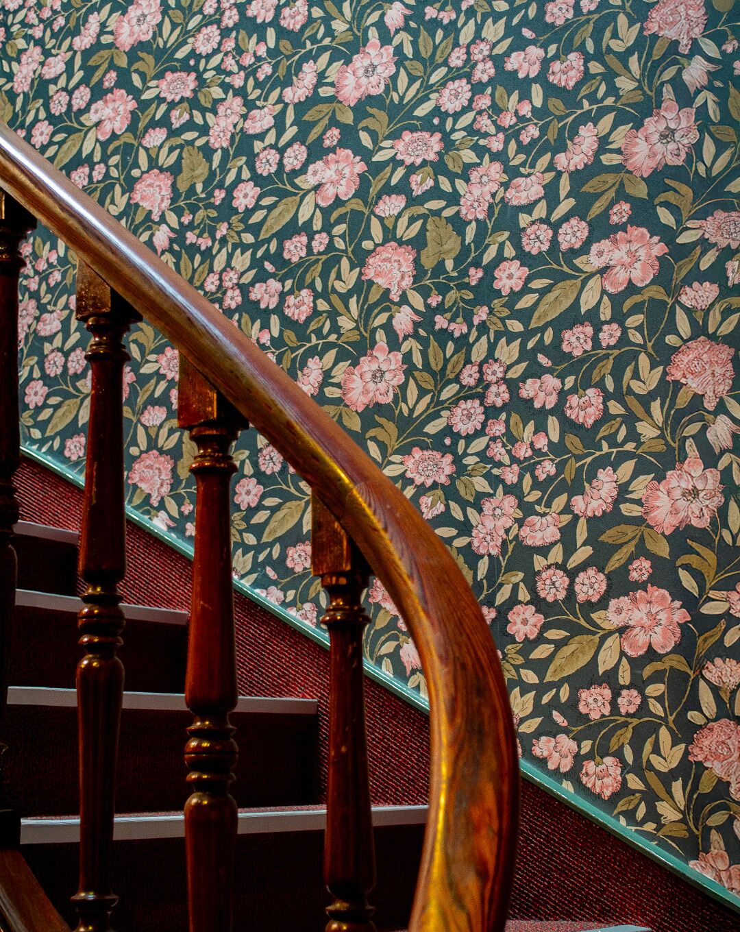 Eine Holztreppe mit floralem Wandpapier.